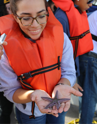 woman wearing glasses and a orange life vest holding a starfish