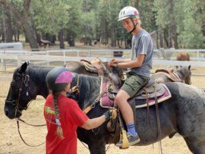 young man on black horse and a person helping guide him on the horse